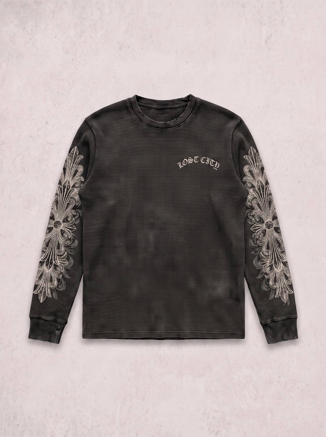 Washed black thermal longsleeve, engraved filigree down both sleeves, small arched Lost City wordmark on the chest