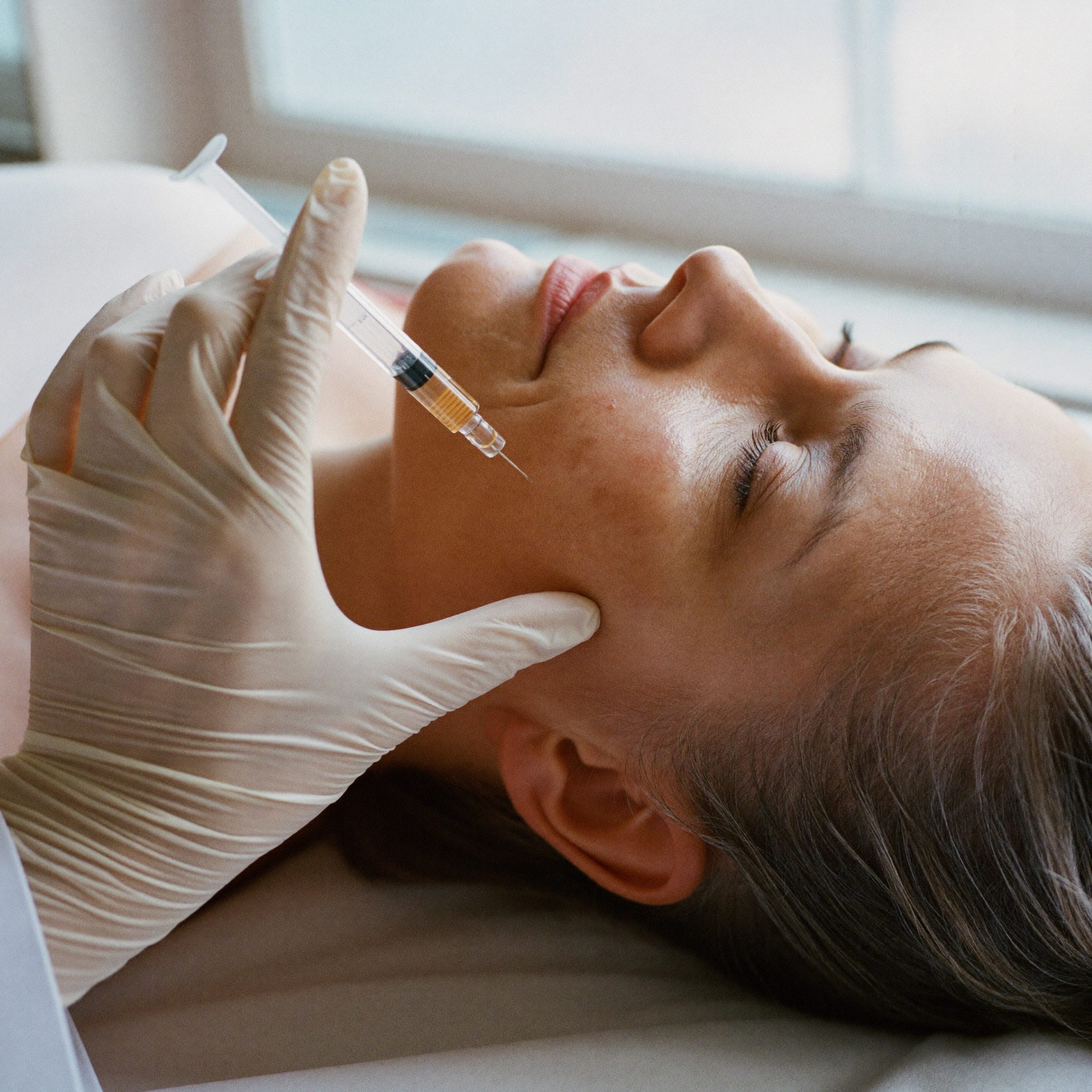 A gloved doctor's hands at a patient's lower face