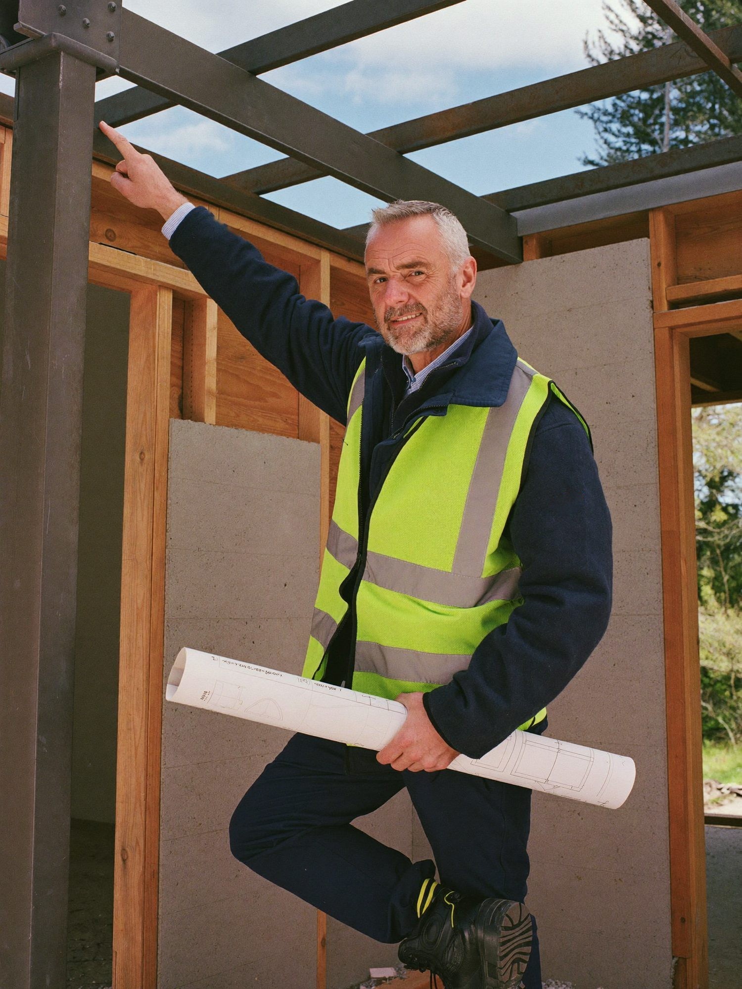 Steve Pearce, site manager, on a timber frame holding rolled drawings